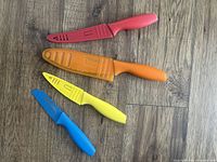 Four colorful knives laid flat showing covers on three knives and the blue knife without cover.