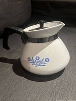 Photo of the vintage Corning Ware 6 cup tea kettle showing front and side with floral design and handle.