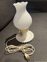 White milk glass hobnail lamp fully assembled with electric cord on side.