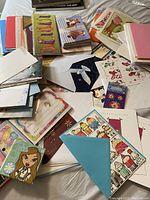 Photo showing a large number of assorted greeting cards spread out on a bed including cards with animals, stockings, and other decorative designs.
