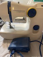 Side view of sewing machine showing multiple stitch pattern options and the foot pedal included