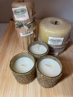 Lot consisting of one large round pillar beeswax candle, one bundle of tapered beeswax candles, and three decorative votive candles.