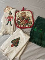 Three Christmas-themed small towels and one hot pad arranged on a flat surface.