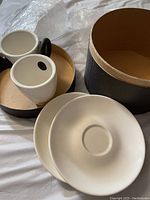 Espresso cups with silicone handles alongside a saucer and packaging box showing lot items.