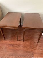Pair of wooden rectangular end tables with warm wood finish and decorative grooved legs.