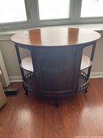 Front view of antique oval wooden storage cabinet with a polished top and central door.
