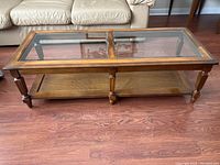 Full front view of the two-tier coffee table with a glass top divided into two panels and cane shelf underneath