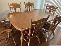 Photo showing the full set of six chairs around the dining table with the leaf extension visible in the center.