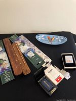 Top view of all items on black table including wooden incense holders, gardenia incense sticks packaging, blue ceramic relish dish with bird motif, and Zippo lighters with boxes