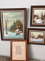 Front view of four framed pieces on wall, showing three winter landscape paintings and one framed quote.