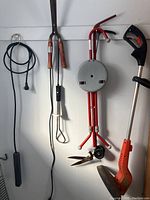 Electric weed whacker, garden shears, cane stool, round water heater or reel and power bar hanging on wall