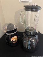 Black & Decker blender with glass jar and control buttons next to Hamilton Beach citrus juicer
