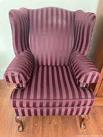 Front view of wingback chair with burgundy and rose vertical striped upholstery, showing padded armrests and backrest.