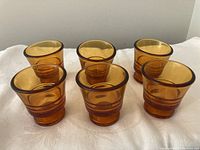 Six retro amber glass egg cups arranged with a front and center view showing all cups.