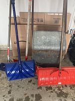 Front view of five snow shovels showing two metal and three plastic shovels with various handle types and blade shapes.