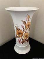 White porcelain vase with floral painting and pedestal base shown from front and side