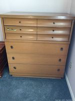 Front view of vintage Kroehler tallboy dresser showing all 5 drawers and wood veneer finish with some wear and 3 stickers on second drawer.
