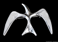 Silver-tone metal bird shaped brooch with outstretched wings and tail feathers, showing front view and reflecting light.