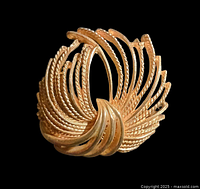 Front view of a vintage 1960s gold-tone brooch with an open circular shape and textured twisted rope details.