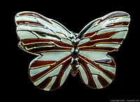 Close-up photo of the enamel butterfly centerpiece showing white and amber enamel with gold-tone metal raised lines