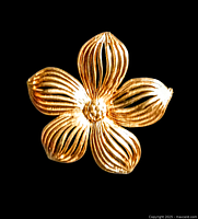 Close-up photo of the vintage gold-tone floral brooch showing five ribbed petals and detailed flower center against a black background.