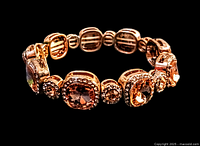 Close-up photo of a vintage stretch bracelet displaying gold-tone metal and clear to amber-colored rhinestones in various shapes with an elastic band.