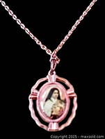 Close-up of rose gold tone pendant showing colored image of St Therese of Lisieux enclosed in oval decorative frame.