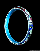 Oblique side view of the round sterling silver cloisonne bangle showing detailed floral enamel design in colors blue, red, white, and green.