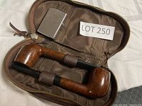 Two wooden smoking pipes secured in leather case with silver metal lighter