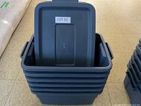 Stack of six gray Rubbermaid storage containers with one lid standing inside the top container.