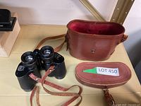 Photo of binoculars, large leather case, and smaller leather case on shelf