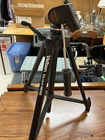 Full view of the Velbon VTB-4600 tripod standing on a wood table in a basement setting.