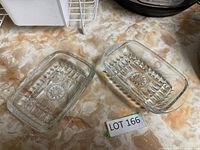Photo of the clear glass butter dish cover placed next to its base on a countertop with a lot label visible