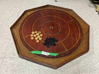Full view of octagonal wooden Crokinole board with game pieces placed on playing surface.