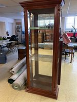 Front view of the tall wooden display cabinet showing glass front and shelves inside.