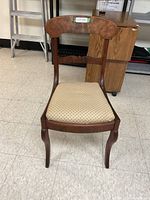 Front view of Duncan Phyfe style wooden chair with upholstered seat and curved legs.