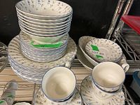 Wide view of stacked plates, bowls, and cups showing floral details and blue rim accents