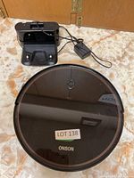 Onson robot vacuum with charging station and power adapter shown on floor.