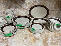 Full set of Royal Doulton Lambethware dishes including mugs, dinner plates, bowls, and smaller plates arranged together showing design and quantity.