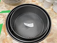 Three black springform cake pans stacked inside each other showing textured non-stick base and metal sides with latch.