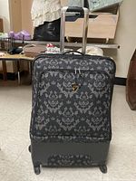 Small black and grey damask patterned suitcase with raised bottom and four spinner wheels, telescopic handle visible