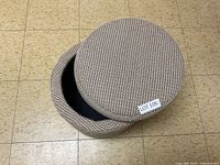 Top view of the round upholstered storage stool with lid removed showing the internal storage compartment.