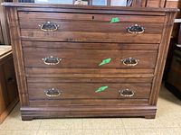 Front view of the vintage wooden dresser showing three drawers with brass handles and keyholes.