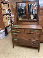Front view of vintage wooden dresser with attached mirror, showing four drawers with metal ring pull handles and visible wear.