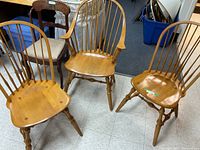 Three light wood Windsor chairs; two armless and one with arms visible in a room with tiled floor
