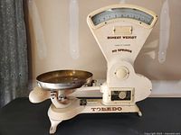 Side view of the entire 1920s Toledo mercantile fan scale showing the metal body, arm, and brass weighing pan.