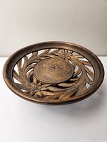 Front side of carved wooden fruit bowl showing floral cutout design with circular raised centerpiece.