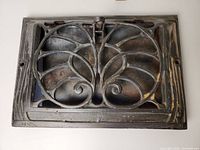 Top-down view of the cast iron vent showing decorative vent grille design and adjustable damper lever in the center.