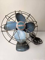 Front view of the Electrohome vintage fan showing blue four blade fan inside metal wire protective cage with central badge