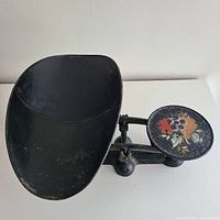 Full front view of the Fairbanks No. 3 candy scale showing the large black rounded scoop and floral painted weighing plate.